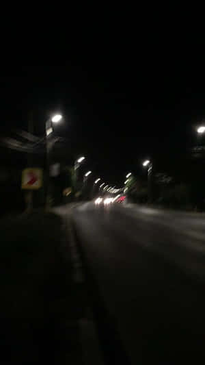 夜間街道場景，街燈和車頭燈呈現動態模糊效果。 — 城市燈光 壁紙