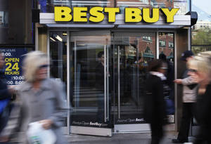在繁忙的城市街道上，行人模糊地經過Best Buy商店入口。