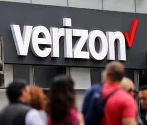 行人走過 Verizon 商店標誌。 — 威訊 壁紙