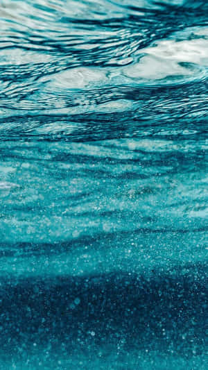 水下碧綠海水，光線穿過水面，形成閃爍圖案。 — 美學藍色 iPhone 壁紙