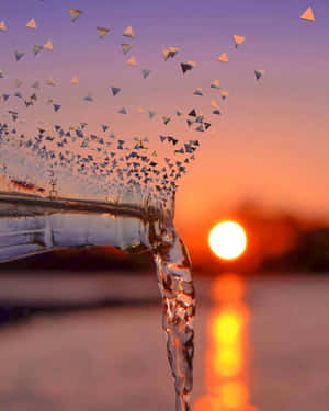 水從玻璃瓶傾瀉而出，三角形玻璃碎片在夕陽背景下漂浮。 — 海灘日落 壁紙