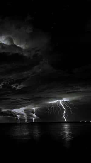 夜晚暴風雲下，黑暗水面上閃電擊中。 — 閃電 壁紙