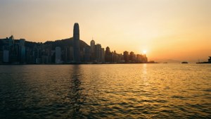 金色夕陽下的香港天際線倒映在平靜的海港水面上。 — 香港 壁紙