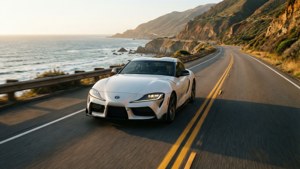 白色跑車在日落時分沿著蜿蜒的海岸公路飛馳。 — Toyota Supra 壁紙