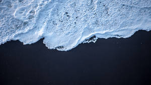 白色的泡沫海浪從上方與深黑色的沙灘相遇。 — 海景 壁紙