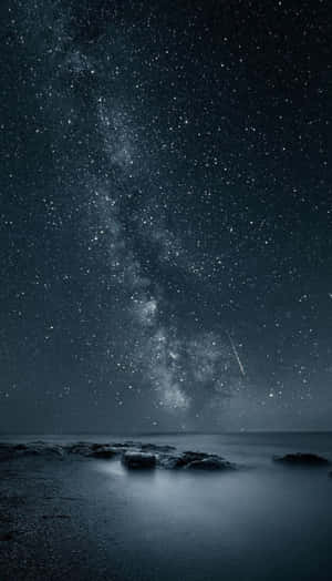 夜間海洋上空的銀河系，伴有流星和岩石海岸。 — 夢幻 GIF 壁紙