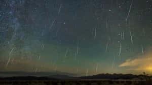 流星雨劃過山脈輪廓上方的星空夜空。 — 星星 壁紙