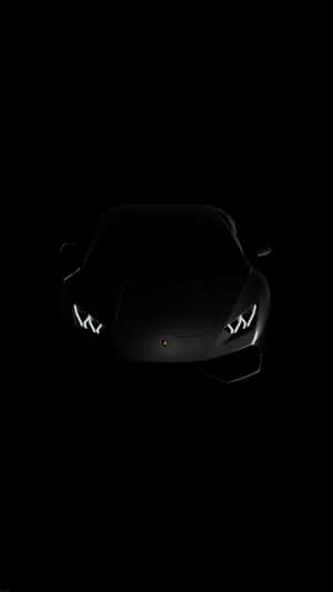 在完全黑暗中車頭燈發光的黑色藍寶堅尼。 — 悟空黑 iPhone 壁紙