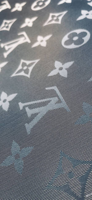 深灰色布料，帶有白色 Louis Vuitton 字母圖案和花卉圖案。