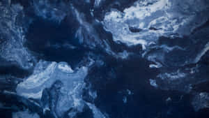 深藍色和白色的抽象旋轉圖案，類似海浪或宇宙雲。 — 美學大理石 壁紙