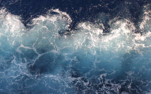 從上方觀看，深藍色海水上翻騰海浪帶白色泡沫。 — 海洋桌面 壁紙