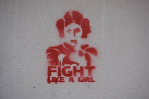 牆上的紅色塗鴉藝術，展示了一個女人和「fight like a girl」的字樣。 — 星際大戰 壁紙