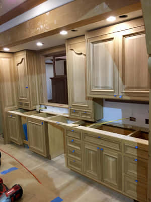木質廚房櫥櫃正在施工中，帶有藍色遮蔽膠帶和地板上的工具。 — 室內設計 壁紙