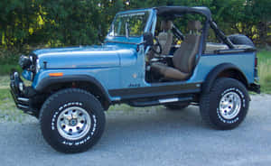 藍色Jeep Wrangler，米色座椅，停放在碎石路上，附近有樹木。 — Steam Deck OLED 壁紙