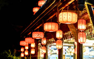 傳統紅色燈籠在夜間照亮木建築，前景有竹子。 — 綠光戰警 壁紙