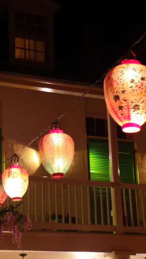 一串發光的紙燈籠在夜間掛在房子外面。 — 午夜 壁紙