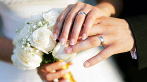 情侶雙手交握，捧著白玫瑰，結婚戒指清晰可見。 — 婚禮 壁紙