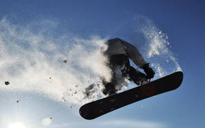 滑雪板運動員在半空中噴灑雪花，以藍天為背景 — X Games 壁紙