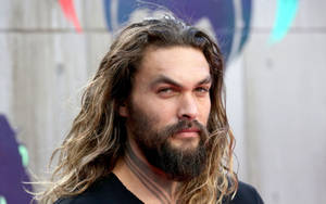 演員傑森摩莫亞（Jason Momoa）留著長髮和鬍鬚，在戶外表情嚴肅。 — 傑森·摩莫亞 壁紙
