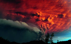 火山爆發，熾熱的火山灰雲映襯著暮色天空和樹木剪影。 — 黃昏 壁紙