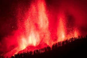 火山爆發，在黑暗的森林背景下，噴出明亮的紅色熔岩和火花。 — MacBook Pro 14 壁紙