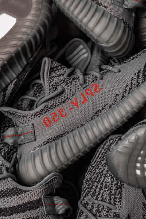 一堆灰色 Yeezy Boost 350 運動鞋，帶有紅色品牌細節。 — 肯伊·威斯特 壁紙