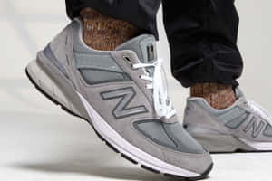 灰色New Balance運動鞋搭配白色鞋帶和圖案襪子。 — New Balance 壁紙
