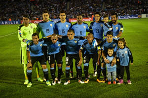 烏拉圭足球隊和孩子們在夜間燈光明亮的球場上合影。 — FIFA 世界盃 壁紙