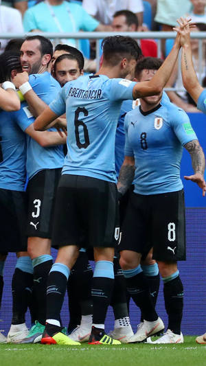 烏拉圭足球隊在綠色球場上慶祝進球。 — FIFA 世界盃 壁紙