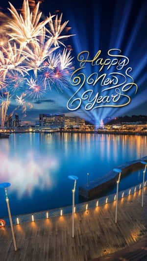 夜晚城市天際線上空的煙火，水面上閃耀著「Happy New Year」文字。 — 新年快樂 壁紙