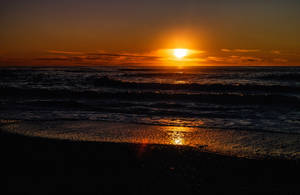 海上的夕陽，海浪沖刷深色沙灘。 — 俄勒岡州 壁紙