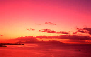 海洋上鮮豔的粉紅色和橙色夕陽，山巒剪影 — 美學天空 壁紙