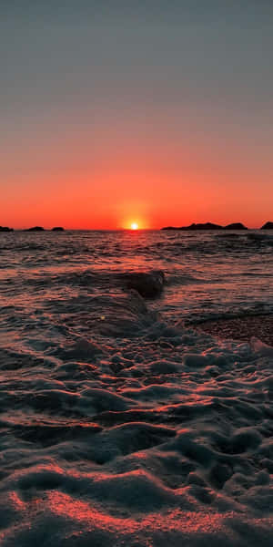 海上日落，海浪拍岸，遠處有島嶼 — 城市燈光 壁紙