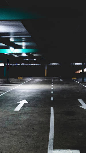 空無一人的地下停車場，帶有白色方向箭頭和綠色天花板燈。 — 箭頭 壁紙