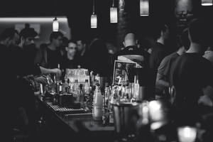 人們在繁忙的酒吧中社交，調酒師在吊燈下調製飲品。 — 酒吧 壁紙