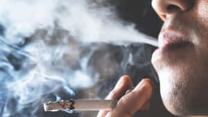 手持點燃的香煙呼出煙霧的人。 — 抽菸 壁紙