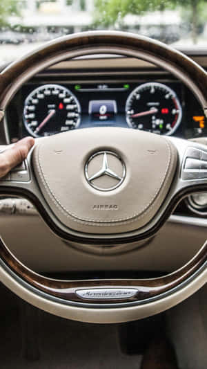 手放在 Mercedes-Benz 方向盤上，帶有木質飾邊和數位儀表板。 — Mercedes Benz C300 壁紙