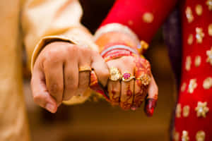 一對新人在傳統婚禮上緊握雙手，帶有指甲花和金戒指。 — 婚禮 壁紙