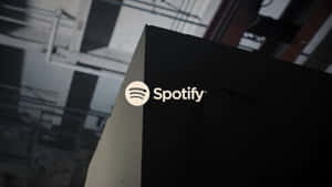 在工業環境中，黑色盒子上點亮的 Spotify 標誌。 — Spotify 壁紙