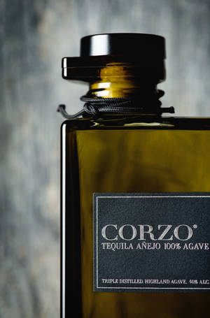 一款豪華龍舌蘭酒瓶，標有 Corzo Añejo，帶黑色瓶蓋和紋理灰色背景。 — 榮耀MagicPad4 壁紙