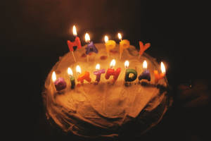 一個生日蛋糕，在黑暗環境中點燃蠟燭拼出 happy birthday 字樣。 — 蛋糕 壁紙