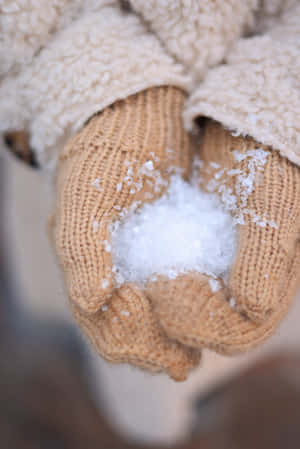 戴著針織手套的手在冬天拿著雪球。 — POCO Pad 壁紙