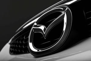 黑色汽車格柵上帶有金屬光澤的閃亮Mazda標誌。 — 馬自達 壁紙