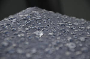 在柔焦中，深色紋理表面上的閃爍雨滴。 — 下雨 壁紙