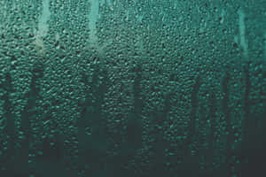 玻璃上的青綠色雨滴，背景模糊 — MacBook Pro M2 壁紙