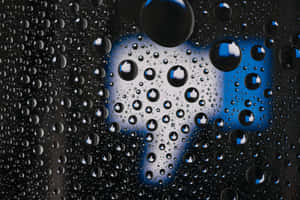 玻璃上的雨滴，背後有一個模糊的藍色豎起大拇指圖示。 — 桌面 壁紙