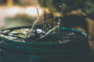 水滴在玻璃碗中向上濺起，背景模糊。 — 水 壁紙