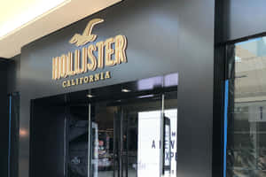 Hollister California商店正面，配有玻璃門和金色標牌。 — 3:2 壁紙