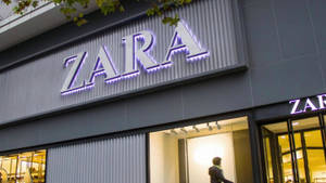 夜晚的Zara服裝店，帶有發光標誌和玻璃窗。 — 霓虹紫 壁紙