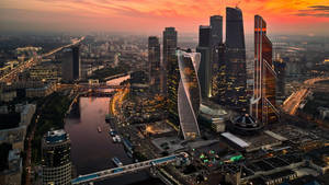 夕陽下的現代城市天際線，閃閃發光的摩天大樓和河流。 — 莫斯科 壁紙